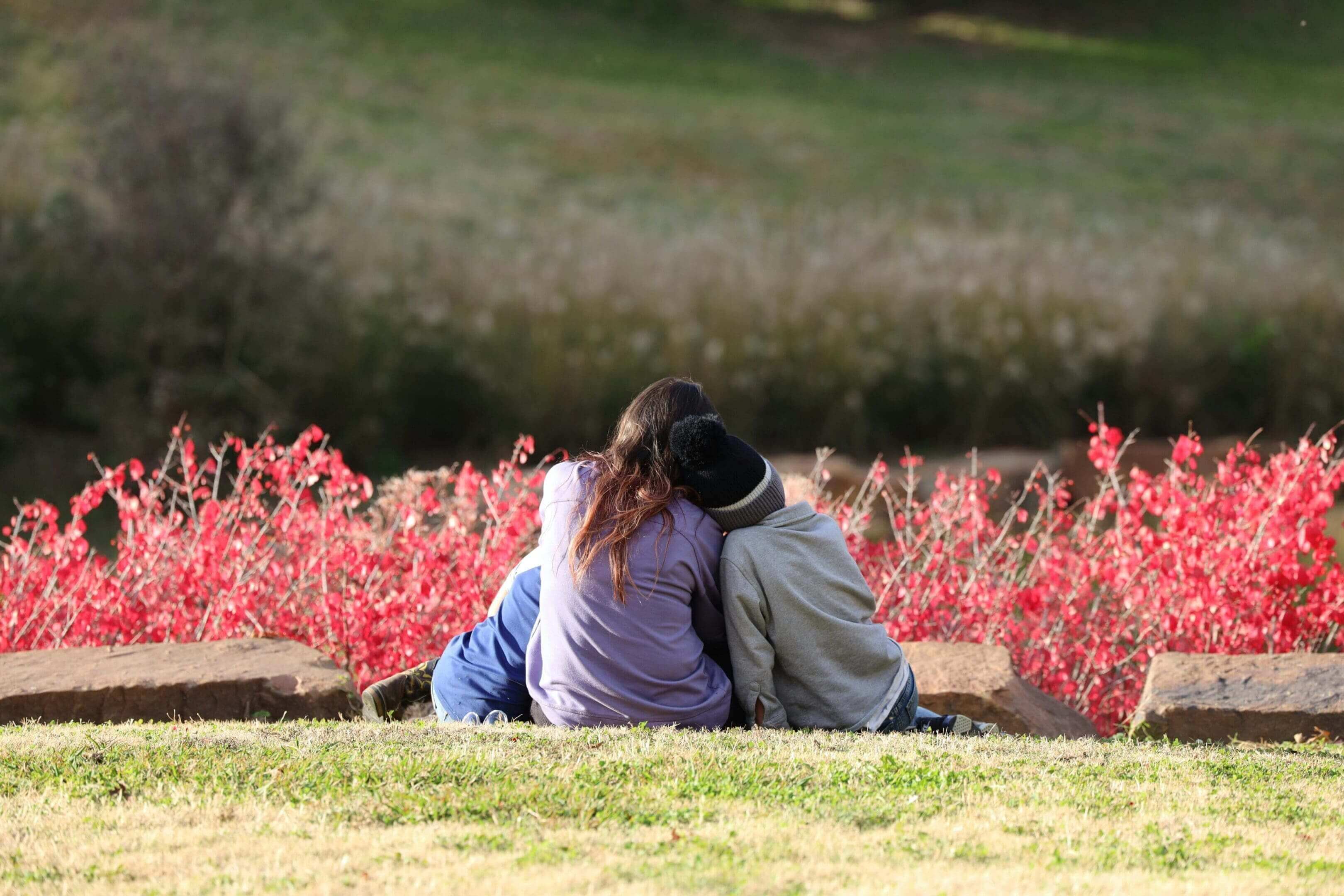 Two children sitting together near flowers.
