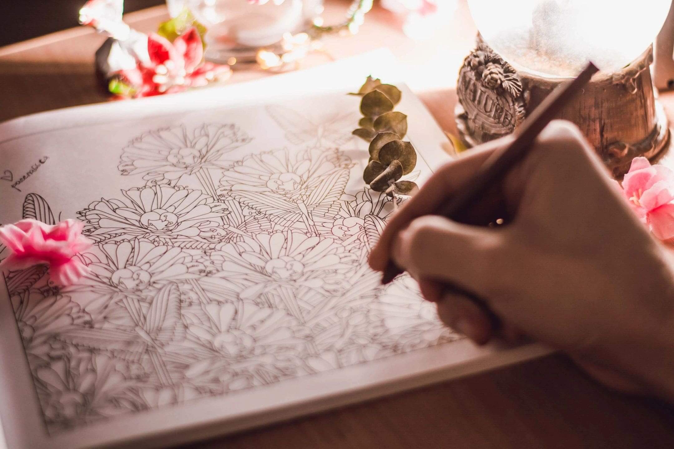 Hand coloring a floral design in a book.
