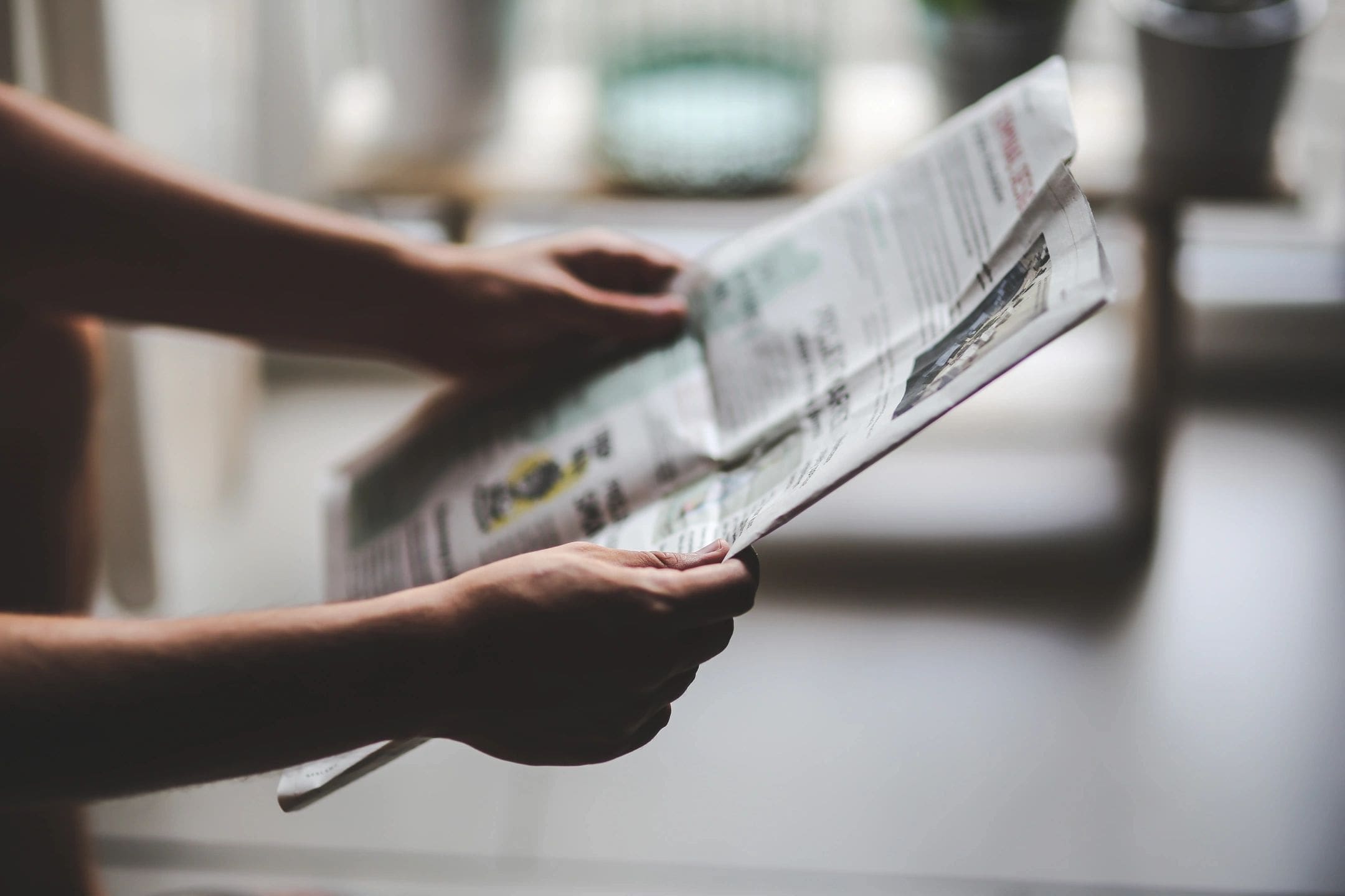 Person reading a newspaper indoors.